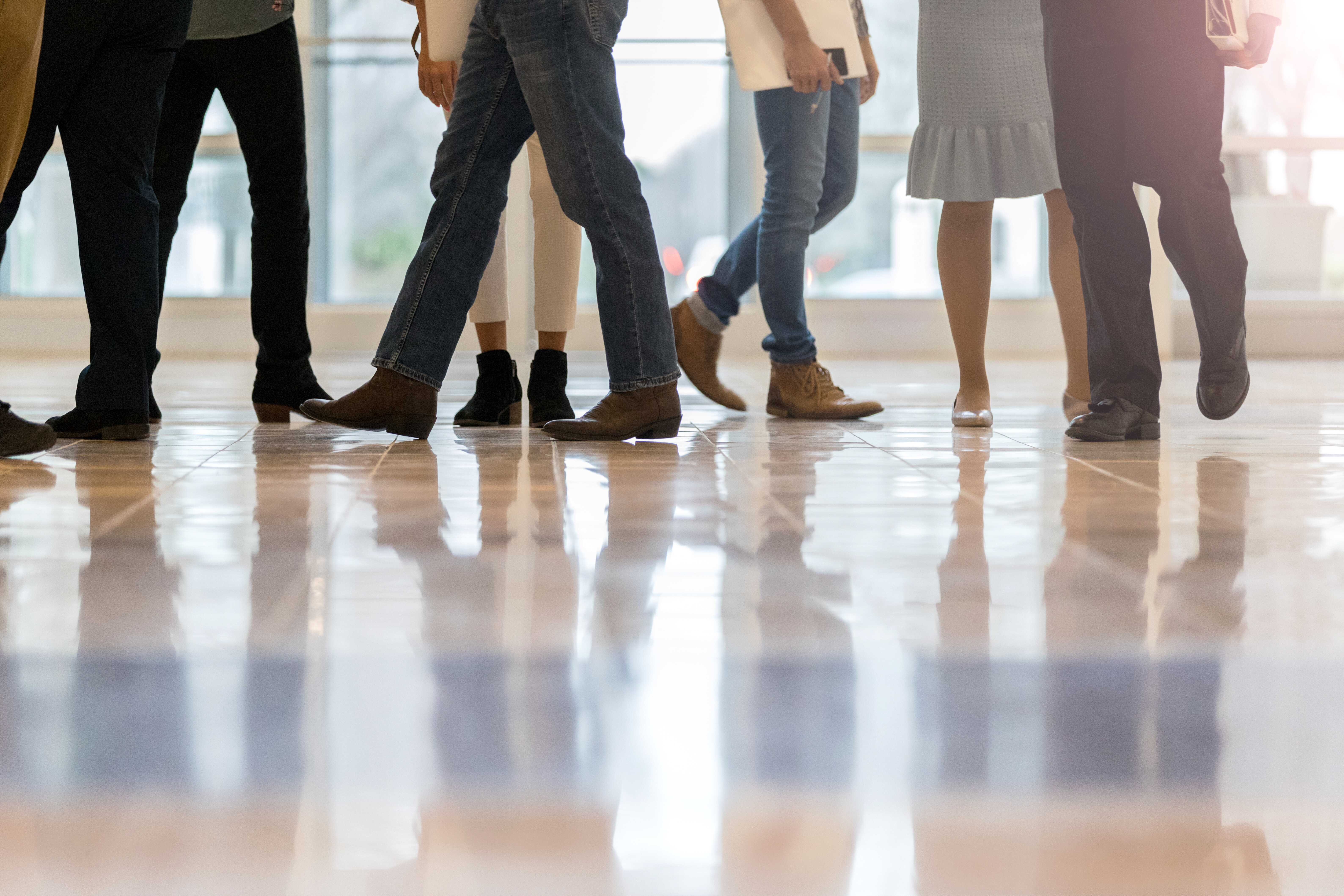 Photo of people's legs and feet walking through a foyer.